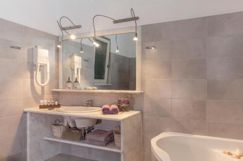 uma casa de banho com um lavatório, uma banheira e um espelho. em Belvedere Beachfront Villa em Afantou