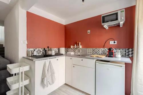 Elle comprend une petite cuisine avec des murs rouges et des placards blancs. dans l'établissement Studio Design et Cosy à 8 min à Pied des Plages, à Cannes