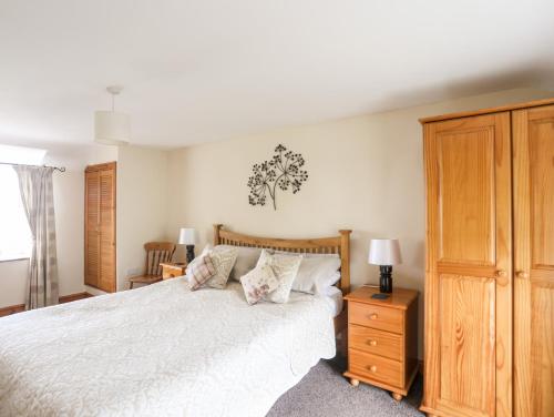 una camera da letto con un letto bianco e un armadio in legno di Moonlight Cottage a Pwllheli