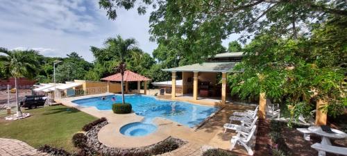 a swimming pool in a yard with chairs and a house at Villa Jr 3 near the peñon guacalillo in Tarcoles