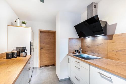 a kitchen with white cabinets and a tv on the wall at Fuchsmichelhof 3 in Seebach