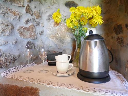 a table with a tea kettle and glasses and flowers at CASA DE CAMPO BENFEITO in Campo Benfeito