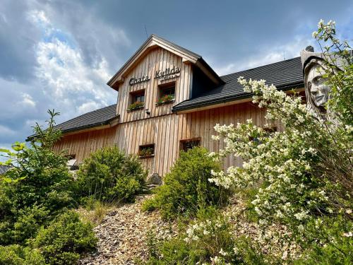 a wooden building with flowers in the windows at Chata Kvilda in Kvilda