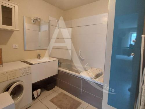 une salle de bain avec un lavabo et une machine à laver dans l'établissement T2 avec terrasse, clim dans le salon, parking a quelques pas des plages, à Sète