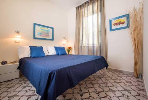 a bedroom with a blue bed and a window at Ravello House in Ravello
