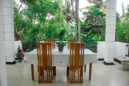a table with four chairs and a white table cloth at Methu Villa in Ahangama