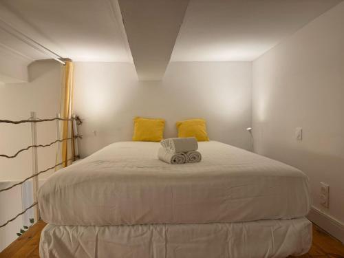 - une chambre avec un grand lit blanc et des oreillers jaunes dans l'établissement Marche aux Fleurs - Premiere conciergerie, à Montpellier