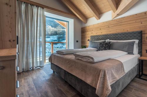 a bedroom with a bed and a large window at Arnica Alpin Lodge in Cavedago