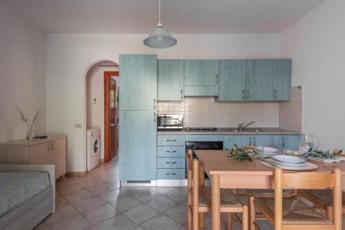 eine Küche mit blauen Schränken und einem Holztisch in der Unterkunft Charming Le Dimore di Budoni 1 Bed Apt B4 sleeps 4 in Budoni