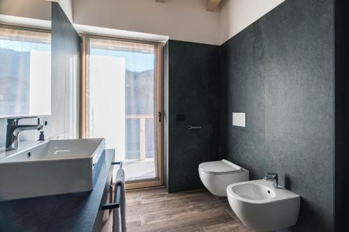a bathroom with a sink and a toilet and a window at Arnica Alpin Lodge in Cavedago