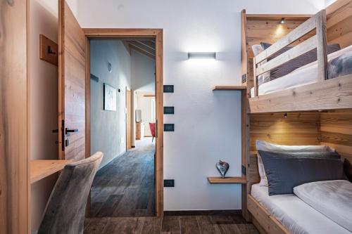 a bedroom with two bunk beds and a hallway at Arnica Alpin Lodge in Cavedago