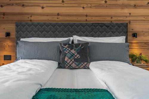 a bed with white sheets and pillows on it at Arnica Alpin Lodge in Cavedago