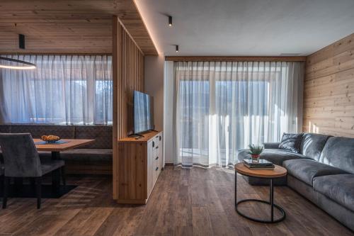 a living room with a couch and a television at Arnica Alpin Lodge in Cavedago