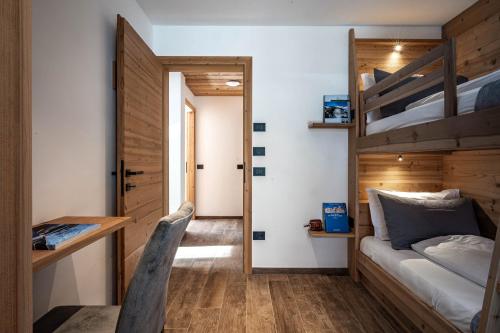 a bedroom with a bed and a desk and a bunk bed at Arnica Alpin Lodge in Cavedago