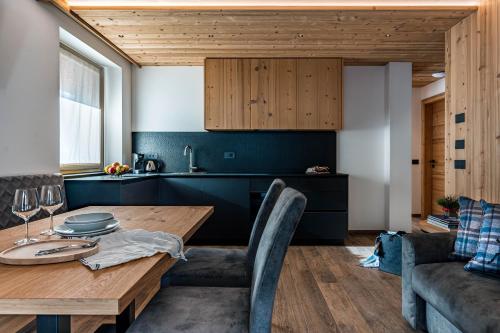 a kitchen and dining room with a wooden table and chairs at Arnica Alpin Lodge in Cavedago
