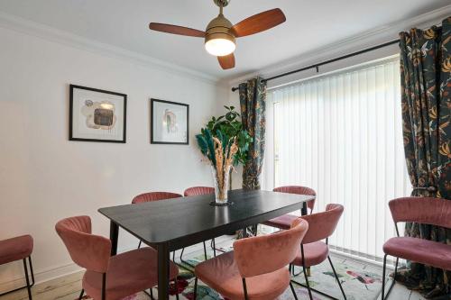 a dining room with a black table and pink chairs at Host & Stay - Cherry Blossom House in Launceston