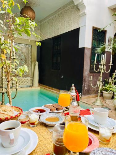 une table avec de la nourriture et des boissons à côté d'une piscine dans l'établissement Riad La Porte Rouge By La Siredrah, à Marrakech