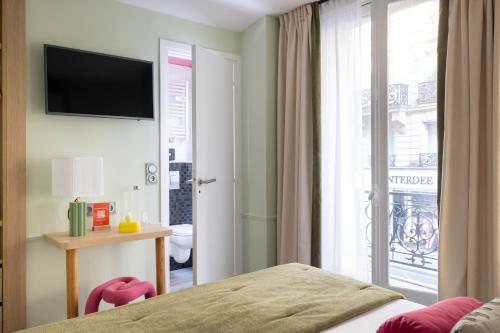 a bedroom with a bed and a sliding glass door at Hotel La Folie des Pres - Saint-Germain-des-Pres in Paris