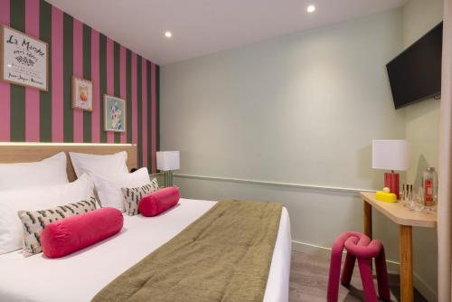 a bedroom with a bed with red pillows and a desk at Hotel La Folie des Pres - Saint-Germain-des-Pres in Paris
