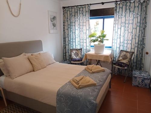 a bedroom with a bed and a table and a window at Casa Susana in Atouguia da Baleia