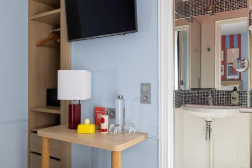 a room with a table with a tv on a wall at Hotel La Folie des Pres - Saint-Germain-des-Pres in Paris