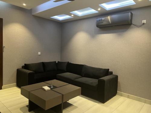 a living room with a black couch and a tv at Courteous Hotel in Islamabad