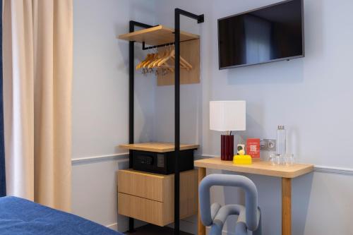 a room with a bed and a desk with a television at Hotel La Folie des Pres - Saint-Germain-des-Pres in Paris