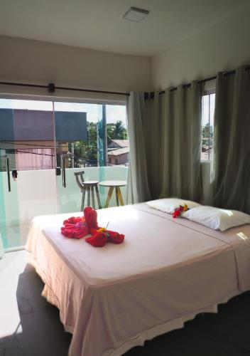 a bedroom with a white bed with red flowers on it at Go Pipa INN in Pipa