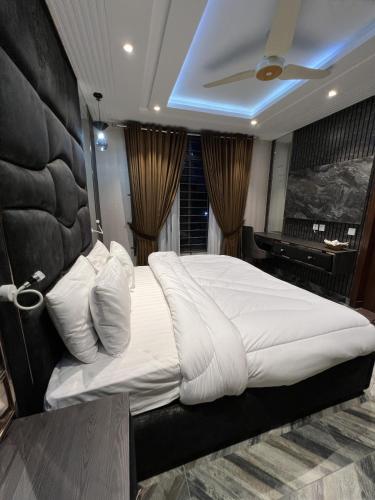 a large white bed in a room with a piano at Courteous Hotel in Islamabad