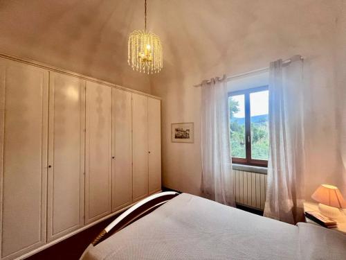 a bedroom with a bed and a chandelier and a window at Villino Rita in Portoferraio