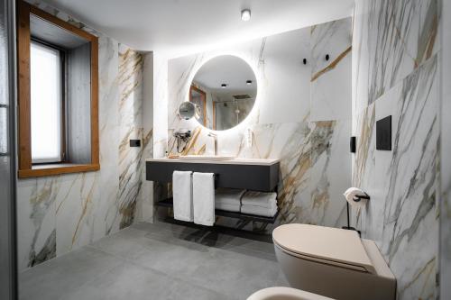 a bathroom with a sink and a toilet and a mirror at Sertorelli Sporthotel in Breuil-Cervinia