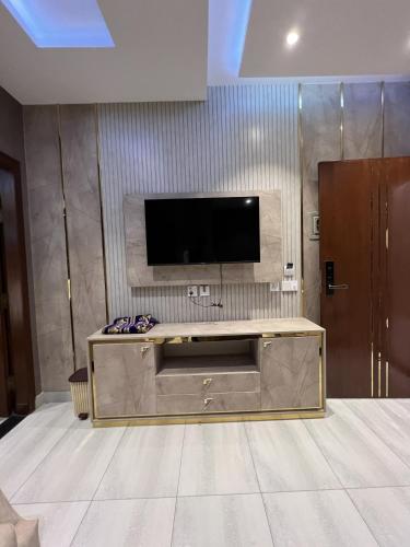 a living room with a flat screen tv on a wall at Courteous Hotel in Islamabad
