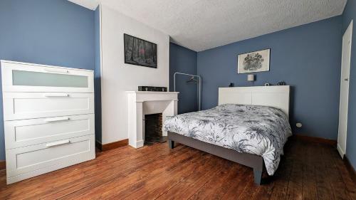 a blue bedroom with a bed and a fireplace at Évasion cosy au cœur du Perche in Boissy-lès-Perche