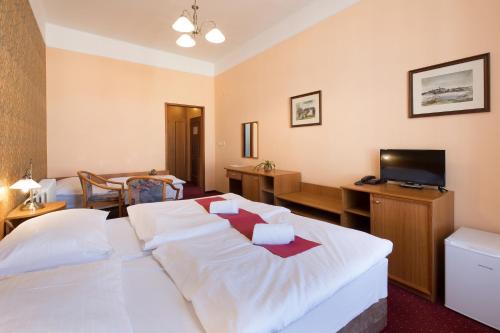 a hotel room with a bed and a television at Hotel U Černého orla in Telč