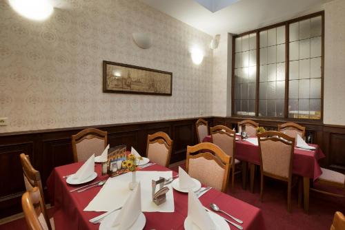 a dining room with tables and chairs with red table cloth at Hotel U Černého orla in Telč