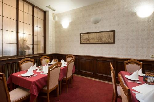 a dining room with tables and chairs with red table cloth at Hotel U Černého orla in Telč