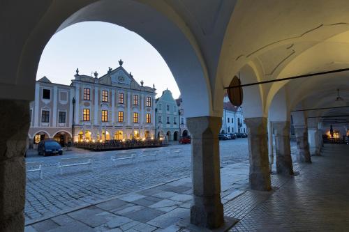 a large building with arches in front of a street at Hotel U Černého orla in Telč