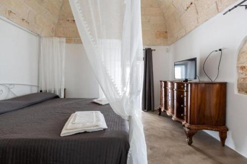 a bedroom with a bed with a dresser and a television at Suite Princess Sophie in Ostuni