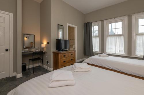 a bedroom with two beds and a desk and a television at Ascot Grange Hotel - Voujon Resturant in Leeds