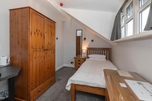 a bedroom with a bed and a wooden cabinet at Ascot Grange Hotel - Voujon Resturant in Leeds