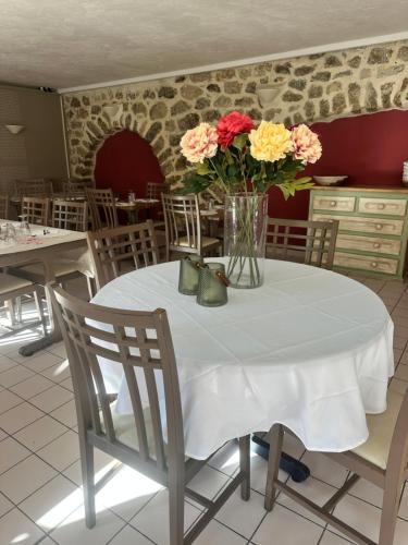 une table blanche avec un vase de fleurs sur elle dans l'établissement Auberge Saint Jo, à Saint-Joseph-des-Bancs