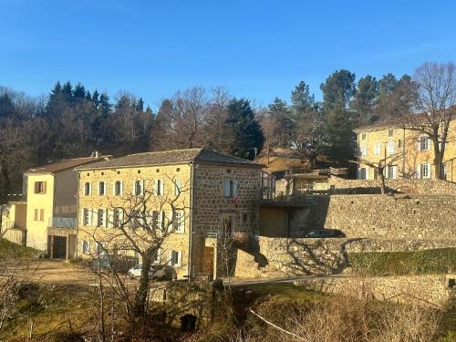 un vieux bâtiment en pierre avec des arbres en arrière-plan dans l'établissement Auberge Saint Jo, à Saint-Joseph-des-Bancs
