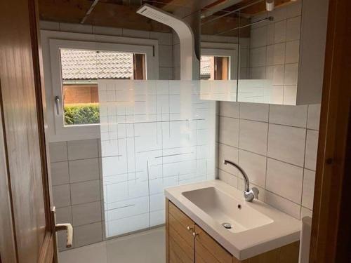 La salle de bains est pourvue de carrelage blanc, d'un lavabo et d'une fenêtre. dans l'établissement Chalet avec jardin, au pied du skibus, proche de Samoens, à Verchaix