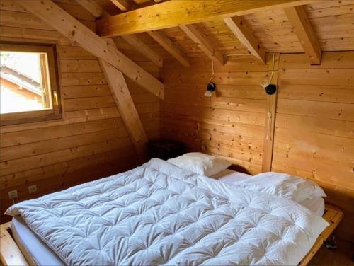 Cette chambre en bois comprend un grand lit blanc. dans l'établissement Chalet avec jardin, au pied du skibus, proche de Samoens, à Verchaix