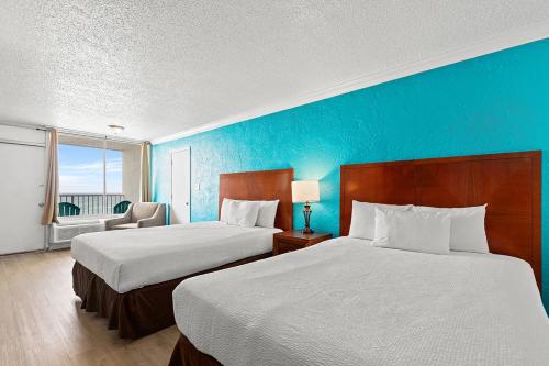 a hotel room with two beds and a blue wall at The Reef At Seahaven Beach Resorts in Panama City Beach