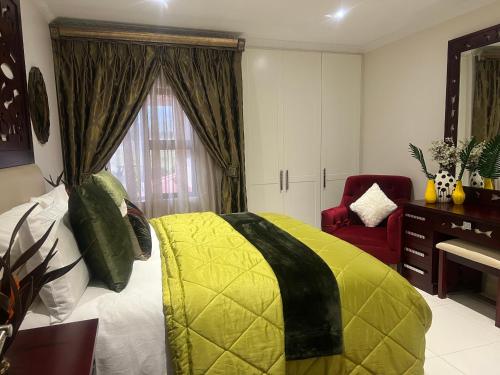 a bedroom with a yellow bed and a red chair at Ambience on N2 Boutique Hotel in Kokstad