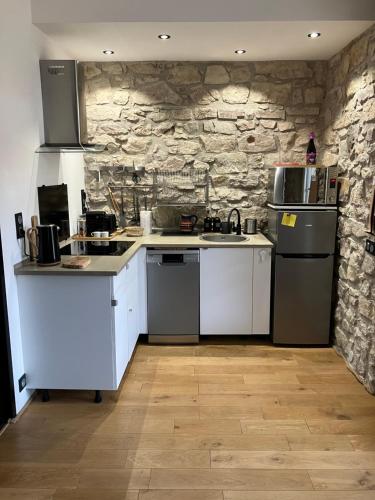- une cuisine avec des appareils blancs et un mur en pierre dans l'établissement Charmant appartement cosy, à Saint-Raphaël