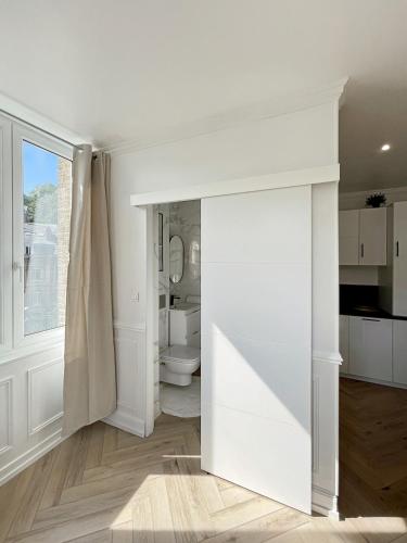 Cette chambre blanche dispose d'une porte menant à une salle de bains. dans l'établissement L'Écrin Dieppois - Proche Plage & Parking Gratuit, à Dieppe