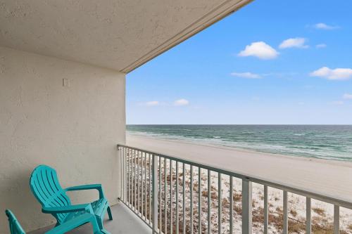 a balcony with a blue chair and the beach at The Reef At Seahaven Beach Resorts in Panama City Beach