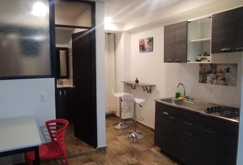 a kitchen with a sink and a counter with a stool at El buen descanso in Fusagasuga